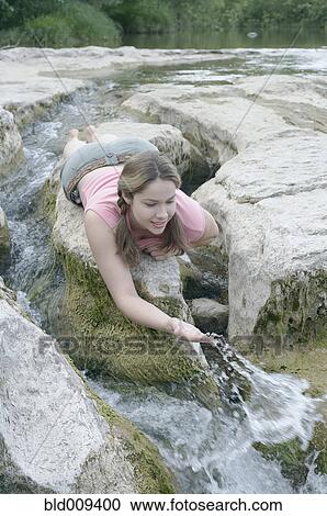 Young woman splashing water in a stream View Large Photo Image Stock Image - Young woman splashing water in a stream. Fotosearch