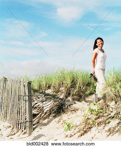 Young woman standing on beach sand dune View Large Photo Image Stock Photo - Young woman standing on beach sand dune. Fotosearch