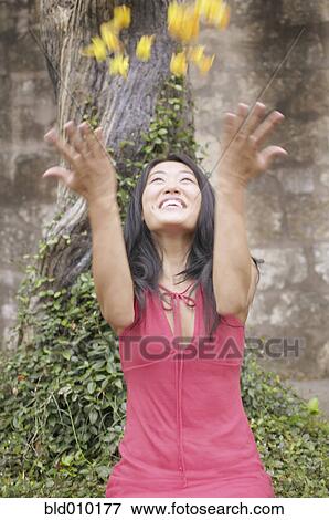 Stock Photo - Young woman tossing flowers in the air. Fotosearch