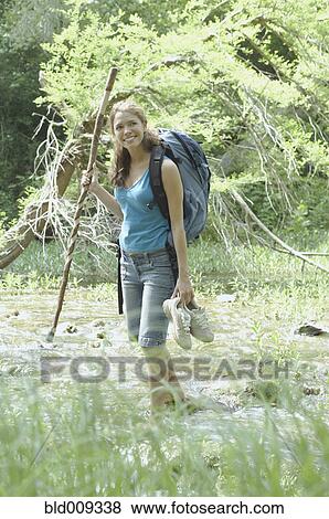 Stock Photo - Young woman wading in forest stream. Fotosearch