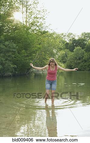 Stock Photograph - Young woman walks in the lake. Fotosearch