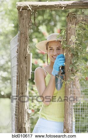 Stock Photo - Young woman wearing gardening gloves. Fotosearch