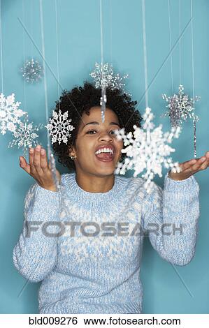 Stock Photograph - Young woman with snowflake mobile. Fotosearch
