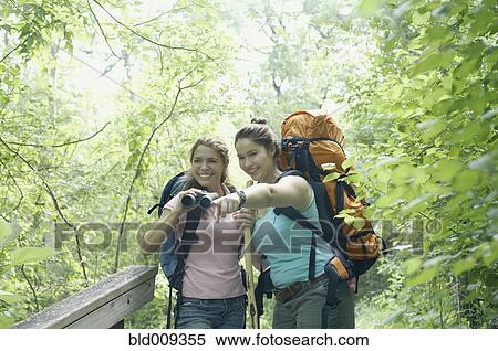 Stock Photography - Young women hiking together in a forest. Fotosearch