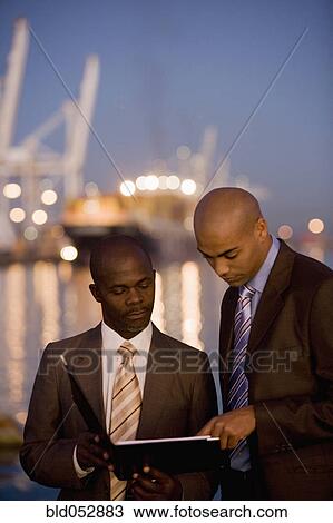 Stock Image - African American businessmen looking at paperwork. Fotosearch