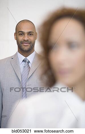 Stock Image - African businessman behind coworker. Fotosearch
