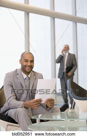 Stock Image - African businessman holding paperwork. Fotosearch