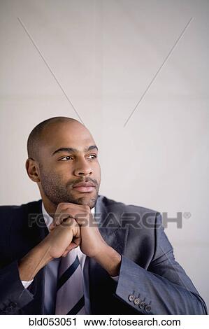 Stock Image - African businessman resting chin on hands. Fotosearch