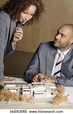 Stock Image - African businesspeople looking at architect's model. Fotosearch