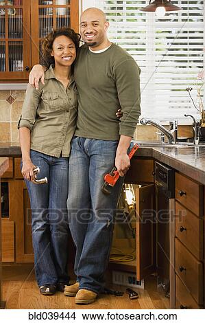 Picture - African couple installing kitchen sink. Fotosearch