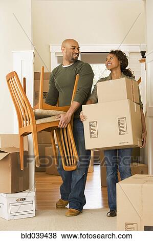 Stock Photo - African couple moving boxes in new house. Fotosearch