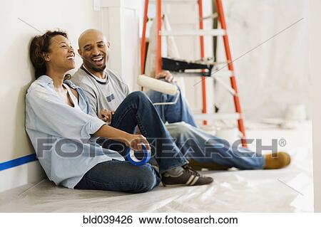 Stock Photograph - African couple taking break from painting. Fotosearch