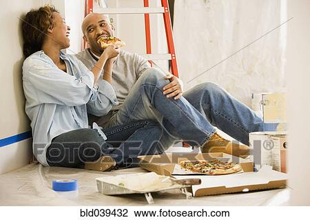 Stock Image - African couple taking lunch break from painting. Fotosearch