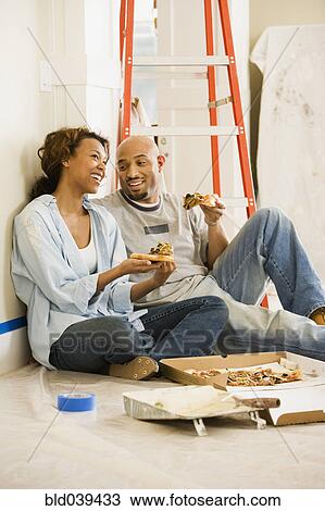 Stock Image - African couple taking lunch break from painting. Fotosearch