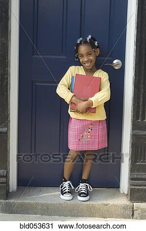African girl holding school books in doorway View Large Photo Image Stock Image - African girl holding school books in doorway. Fotosearch