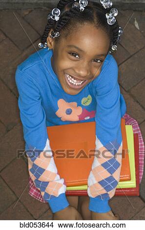 Picture - African girl holding school books. Fotosearch