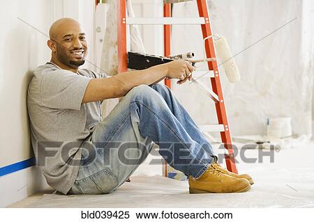 Stock Photography - African man taking break from painting. Fotosearch