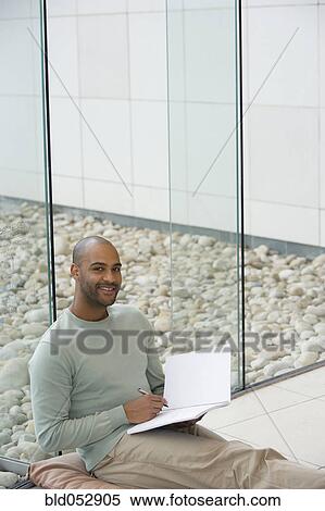 Stock Photography - African man writing in notepad. Fotosearch