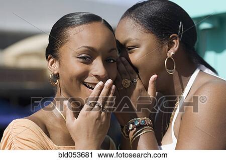Stock Image - African teenaged girls telling secret. Fotosearch
