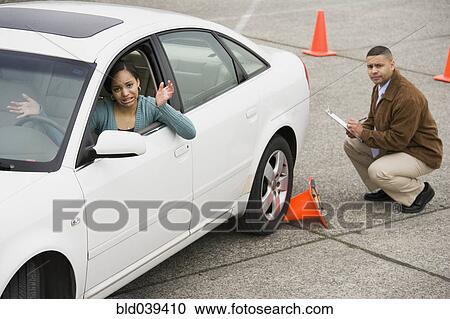 Stock Image - African teenager running over traffic cone at drivers test. Fotosearch