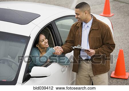 Stock Image - African teenager shaking hands with driving instructor. Fotosearch