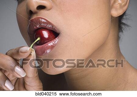 Stock Photography - African woman eating cherry. Fotosearch