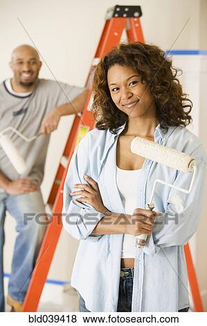 Stock Photo - African woman holding paint roller. Fotosearch