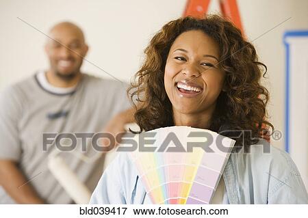 Stock Photo - African woman holding paint swatches. Fotosearch