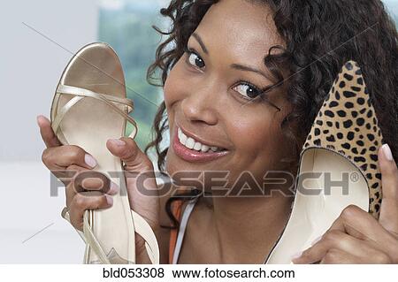Stock Photo - African woman holding up shoes. Fotosearch