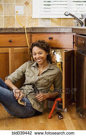 Stock Image - African woman installing kitchen sink. Fotosearch