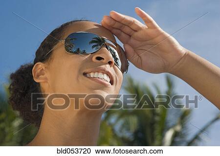 Stock Image - African woman wearing mirrored sunglasses. Fotosearch