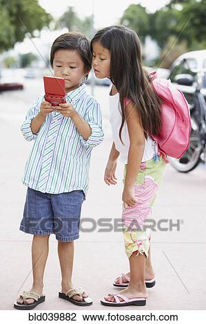 Asian brother and sister playing with handheld game View Large Photo Image Stock Image - Asian brother and sister playing with handheld game. Fotosearch