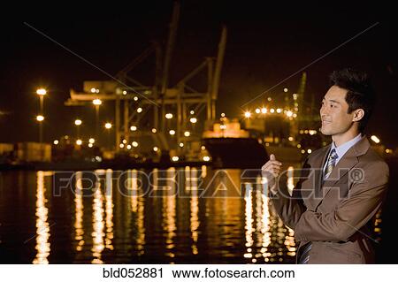 Asian businessman next to water at night View Large Photo Image Stock Image - Asian businessman next to water at night. Fotosearch