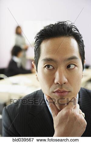 Asian businessman with chin in hand View Large Photo Image Stock Photo - Asian businessman with chin in hand. Fotosearch