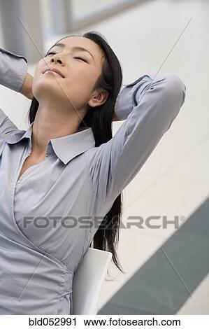 Stock Image - Asian businessman with hands behind head. Fotosearch