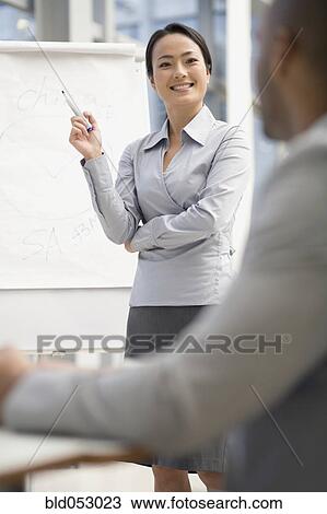 Stock Image - Asian businesswoman giving presentation. Fotosearch