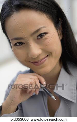 Stock Photograph - Asian businesswoman holding pen. Fotosearch