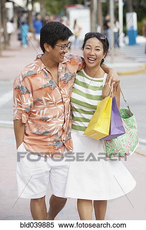 Asian couple walking on sidewalk View Large Photo Image Stock Photography - Asian couple walking on sidewalk. Fotosearch