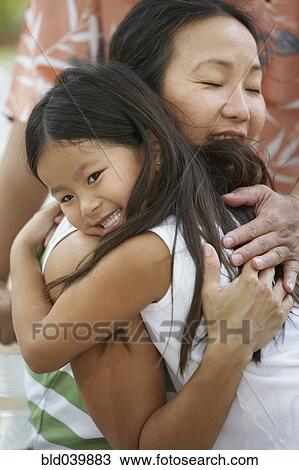 Stock Image - Asian mother hugging daughter. Fotosearch