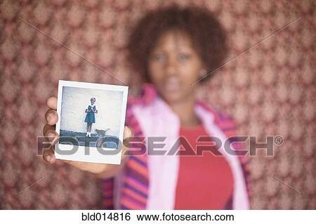 Blurred image of woman holding up old photograph View Large Photo Image Stock Photograph - Blurred image of woman holding up old photograph. Fotosearch