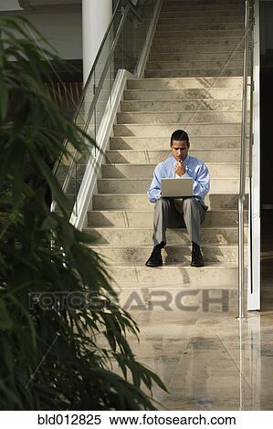 Stock Photography - Business with laptop sitting on steps. Fotosearch