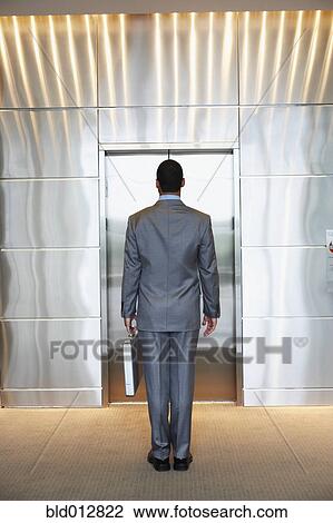 Stock Image - Businessman waiting for elevator. Fotosearch