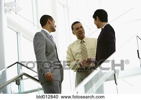 Stock Image - Businessmen shaking hands with woman. Fotosearch