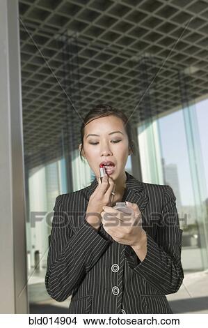 Picture - Businesswoman applying lipstick. Fotosearch