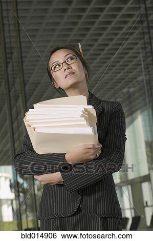 Stock Photograph - Businesswoman holding stack of paperwork. Fotosearch
