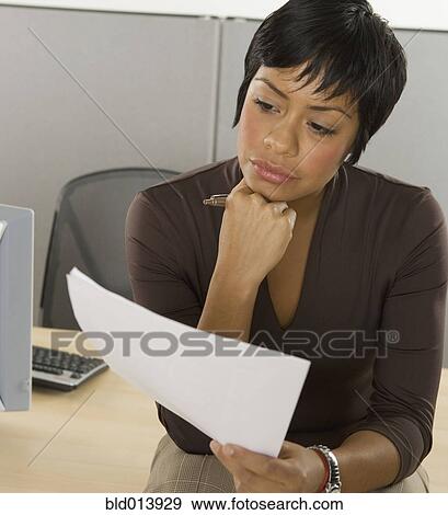 Stock Photo - Businesswoman reading papers at desk. Fotosearch