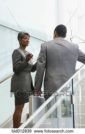 Businesswoman talking to male coworker View Large Photo Image Stock Photo - Businesswoman talking to male coworker. Fotosearch