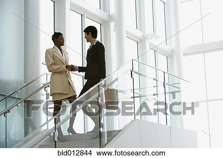 Picture - Businesswomen shaking hands on stairway. Fotosearch
