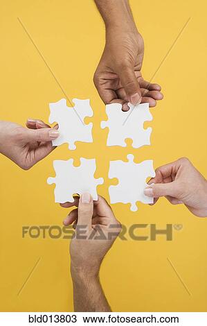 Close up of four hands holding puzzle pieces View Large Photo Image Stock Image - Close up of four hands holding puzzle pieces. Fotosearch
