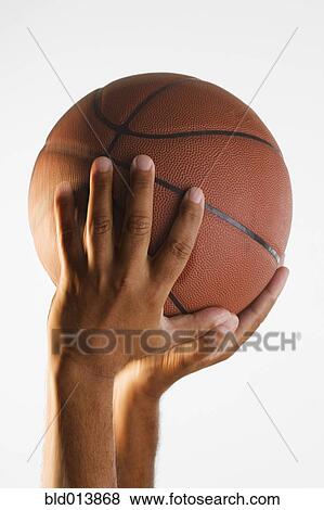 Stock Photo - Close up of hand holding basketball in air. Fotosearch